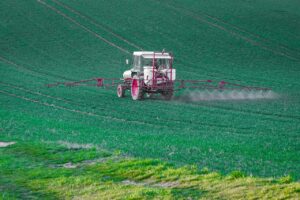 tractor pe campm care aplica tratamente cu pesticide