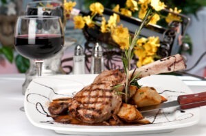 Un pahar de vin lângă o farfurie de friptură