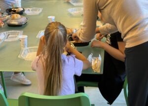 copil care mananca si un adult il ajuta